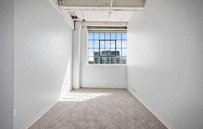 A large empty room with a window overlooking a cityscape.