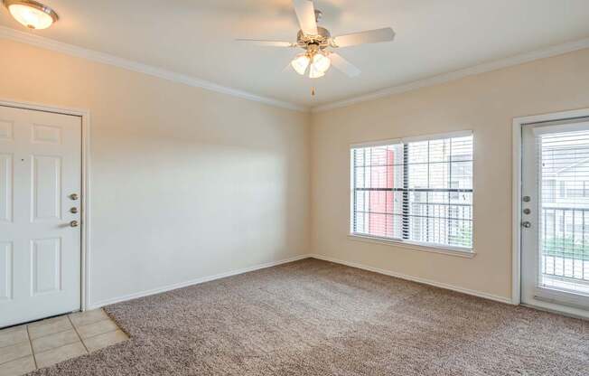 A room with a carpeted floor, a ceiling fan, and a window with blinds.