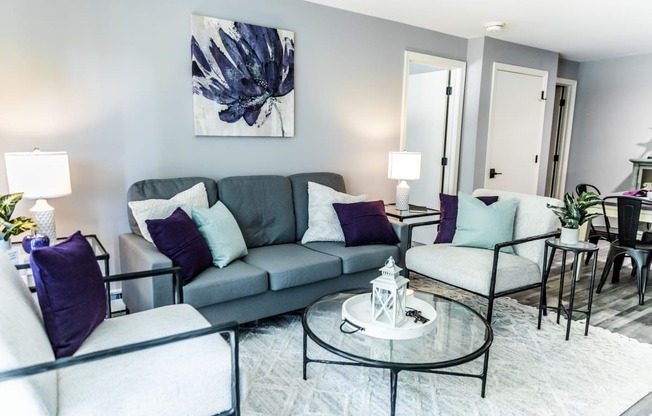 a living room with a gray couch and purple pillows