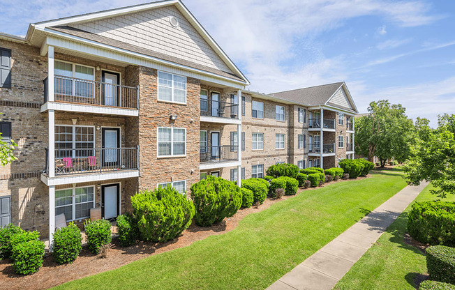 A row of apartment buildings with green bushes in front.
