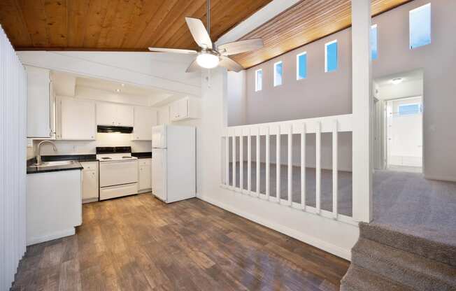 an open kitchen with white appliances and a ceiling fan