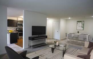 A modern living room with a black sofa and a glass coffee table.