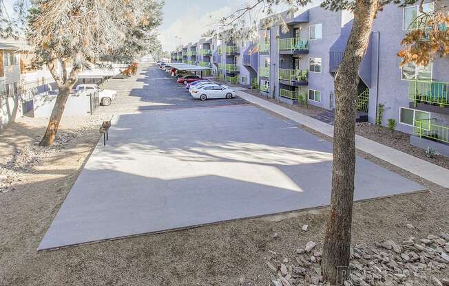 A tree-lined street with apartment buildings on the right.