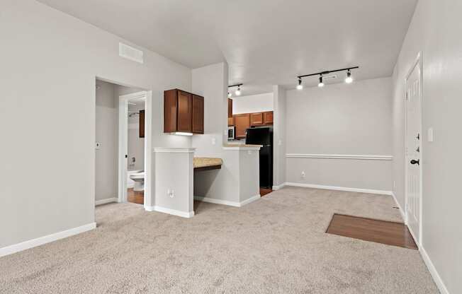 an empty living room with a kitchen with a sink and a window