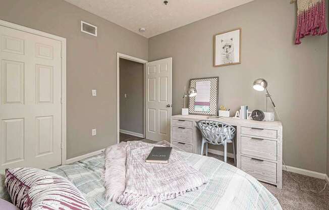 A bedroom with a bed, desk, and chair.