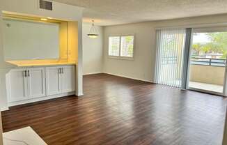 A spacious living room with wood flooring and white cabinetry.