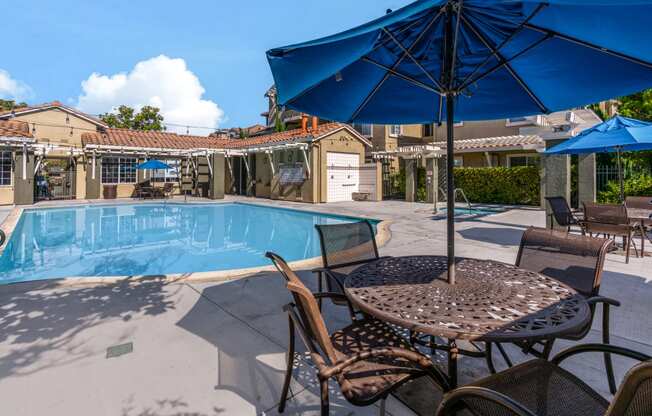 our resort style swimming pool is surrounded by patio furniture and umbrellas