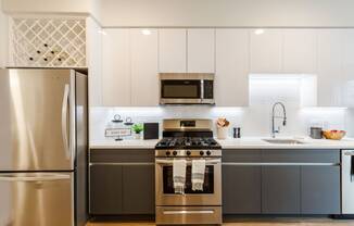 a kitchen with stainless steel appliances and white cabinets at One Ten Apartments, Jersey City
