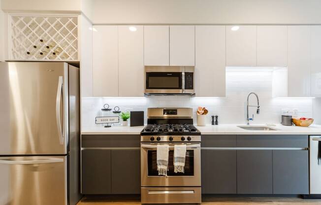 a kitchen with stainless steel appliances and white cabinets at One Ten Apartments, Jersey City