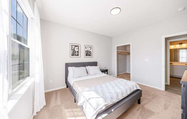 A bedroom with a large bed and a window with curtains.