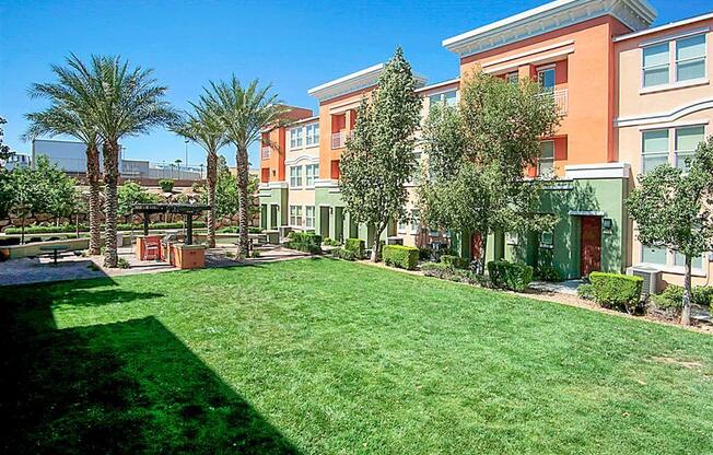 A green lawn in front of a building with trees.