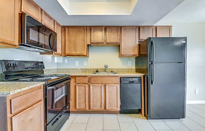 A kitchen with wooden cabinets and black appliances.