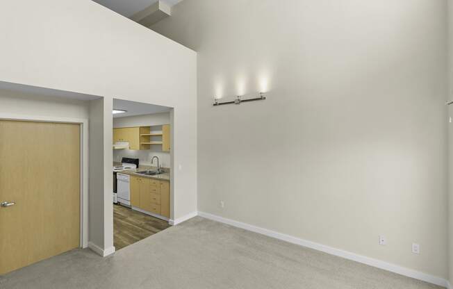 Generous Living Space with Sconce Lighting, a Kitchen View in the Background, and Second Floor at Sir Gallahad Apartment Homes, WA 98004