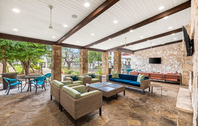 an outdoor living room with couches and chairs and a tv