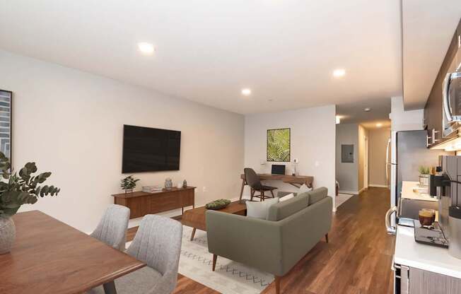 A modern living room with a grey couch, a wooden dining table, and a television.