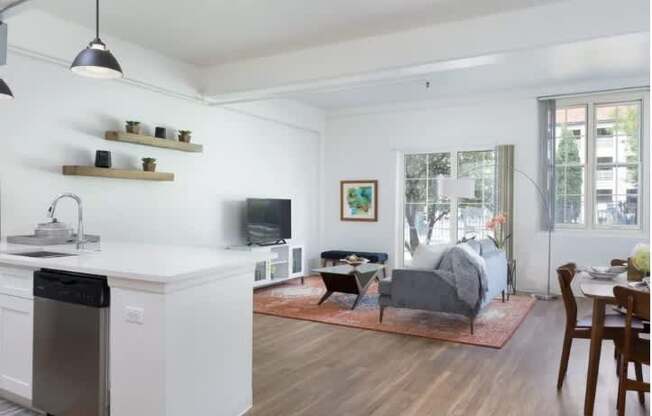 A modern kitchen with a white dishwasher and wooden floors.