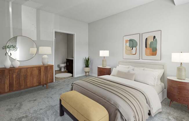 A bedroom with a large bed, a bench, and a mirror.