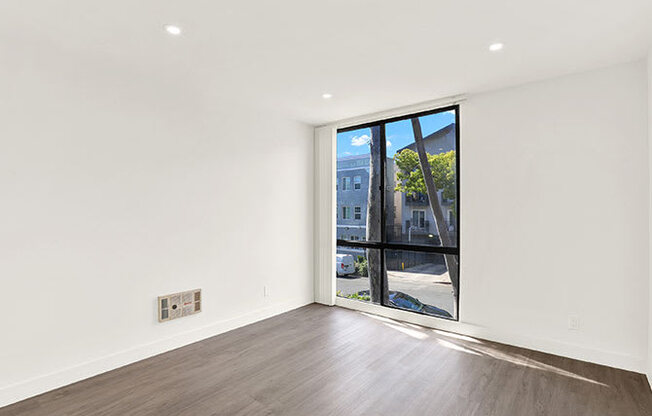 A room with a large window and wooden flooring.