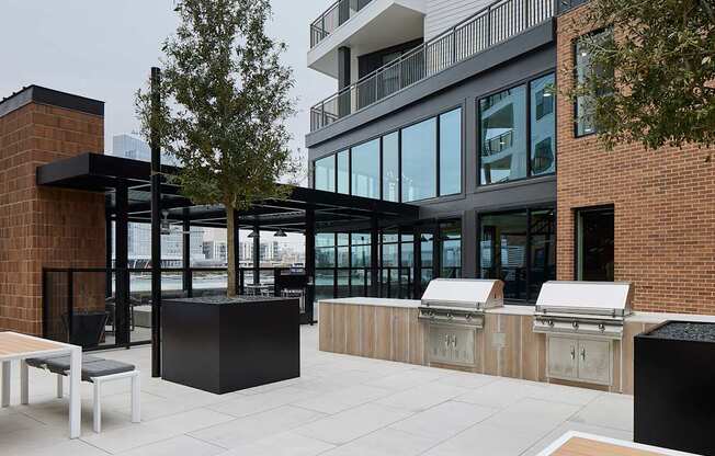 A modern outdoor seating area with a brick wall and a tree.
