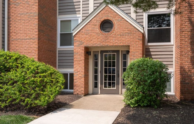 a walkway leads to a brick building with gray siding