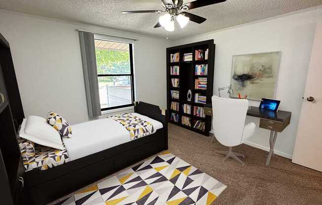 A bedroom with a bed, a chair, and a bookshelf.