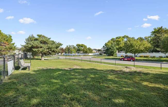 A park with a bench and a fence.
