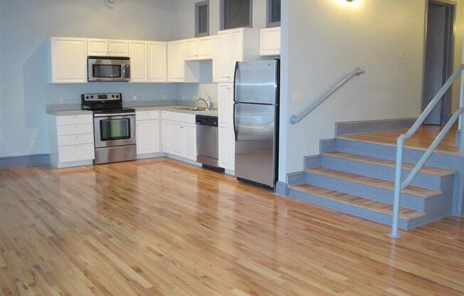 an empty kitchen with a wooden floor and stainless steel appliances at East 4th Street, Cleveland, OH