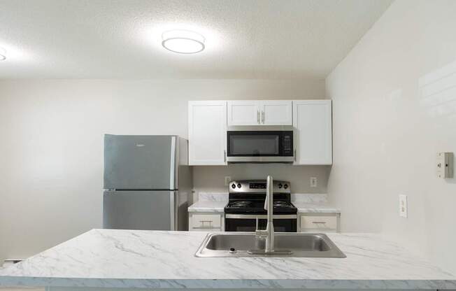 A kitchen with a marble countertop and stainless steel appliances.