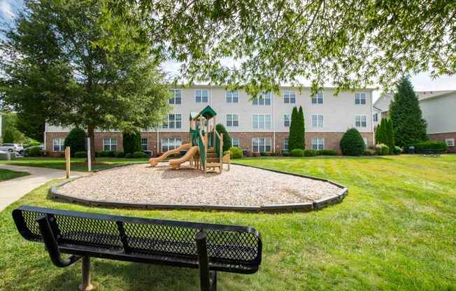 A playground with a slide and a bench in the foreground.