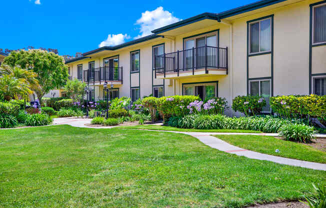 a yard in front of a building with grass and walk ways at Camino de Oro Apartments, Torrance, CA