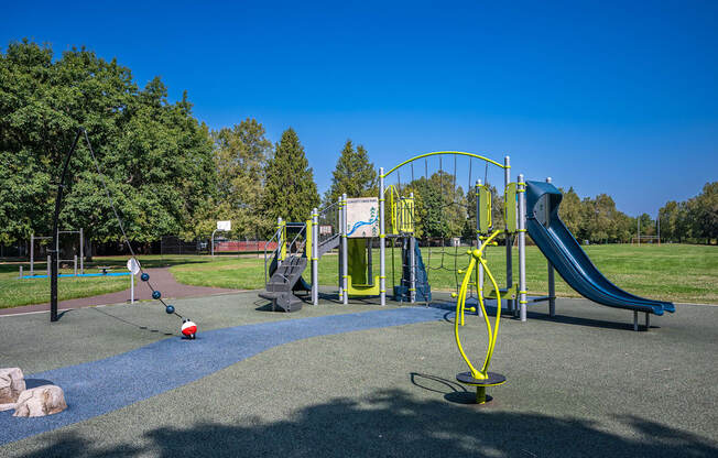 A playground with a blue slide and a yellow swing set.