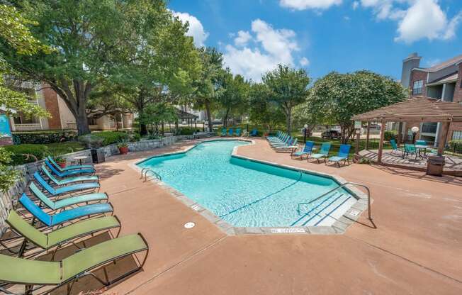 a resort style swimming pool with lounge chairs and umbrellas