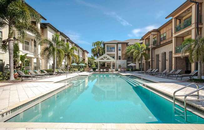 A large swimming pool in the middle of a resort surrounded by palm trees.