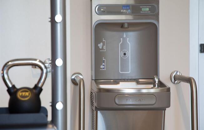 a stainless steel water fountain with a water bottle in front of it
