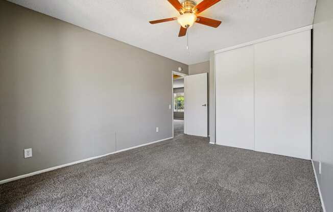 an empty living room with white walls and a ceiling fan