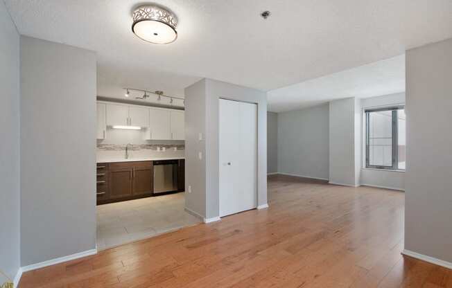 an empty living room with a kitchen in the background