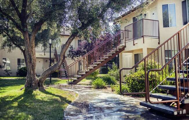 a walkway in front of an apartment building with stairs and trees