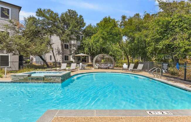 A swimming pool surrounded by trees and chairs.
