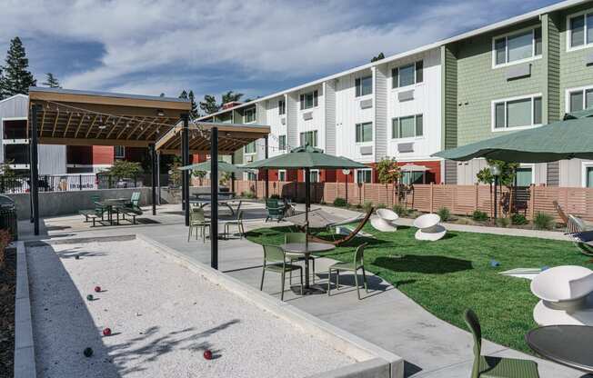 a courtyard with tables and umbrellas in front of an apartment building