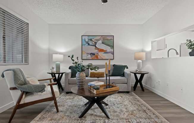 A living room with a grey couch, a wooden coffee table, and a painting on the wall.