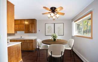 a kitchen with a table and chairs and a ceiling fan. Fargo, ND Country Club Apartments