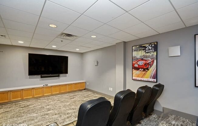 a small conference room with a flat screen tv and leather chairs