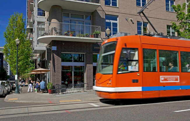 An orange tram is on a city street.