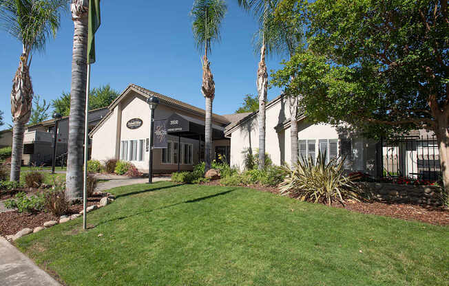 A white clubhouse building with a black awning is surrounded by greenery at Zinfandel Village Apartments, California, 95670