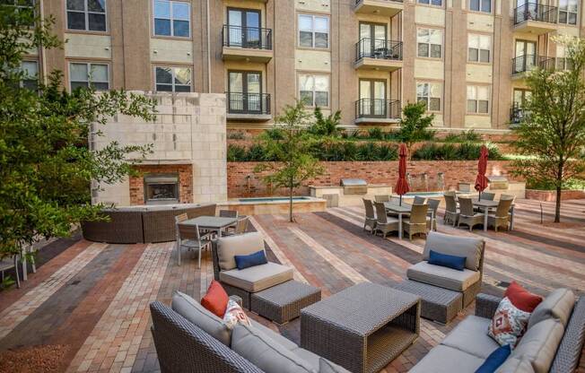 an outdoor lounge area with couches and tables in front of an apartment building