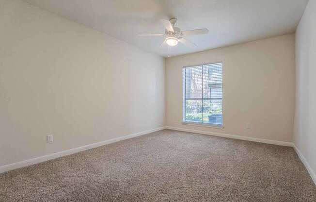 A room with a ceiling fan and carpeted floor.at 2400 Briarwest Apartments, Houston, TX