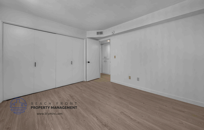 a bedroom with white walls and hardwood floors