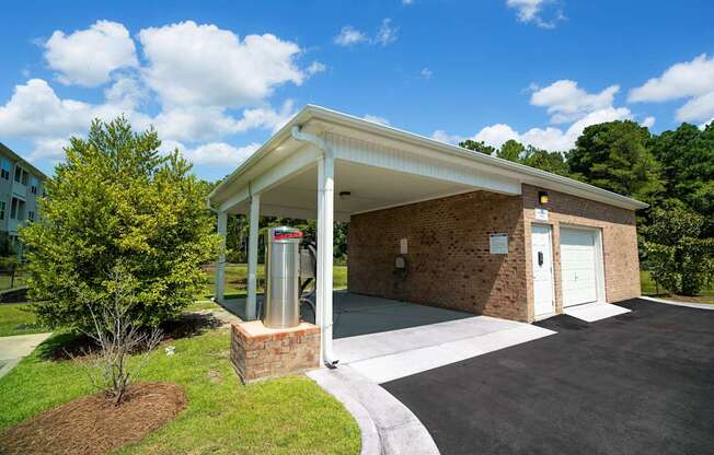 A small building with a white roof and a brick pillar in front of it.