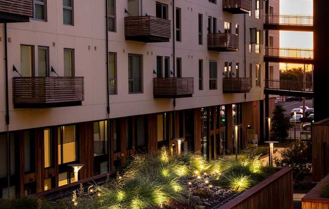 A modern apartment building with balconies and a green roof.