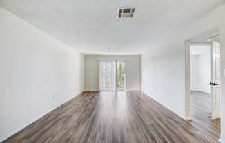 an empty living room with white walls and wood flooring